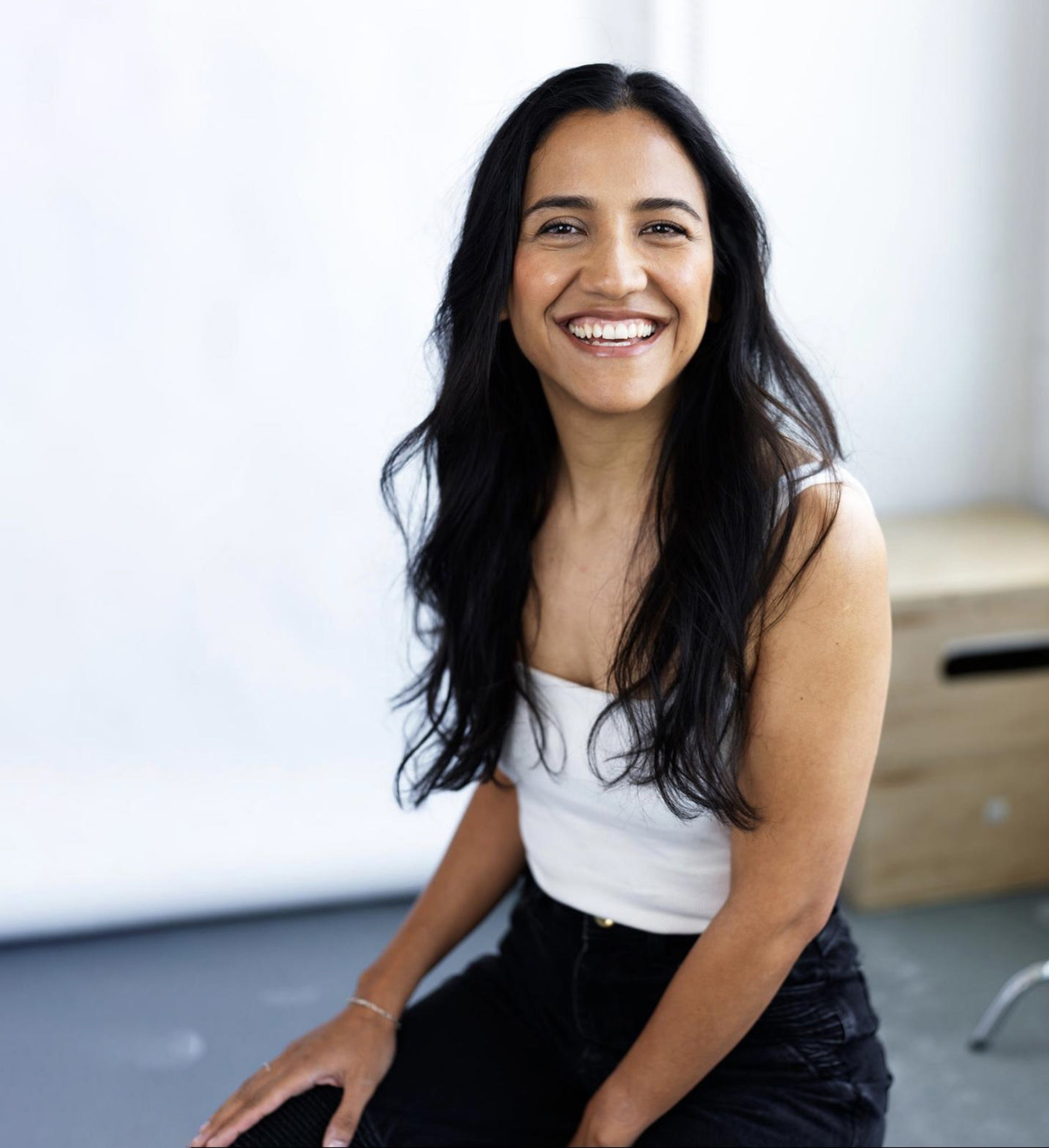 A professional headshot of Priya Karki, the actress, producer, and founder of 8th Day Whisper, smiling warmly at the camera.